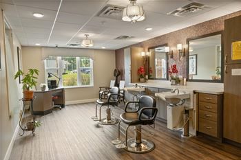 A salon room with chairs and sinks and mirrors